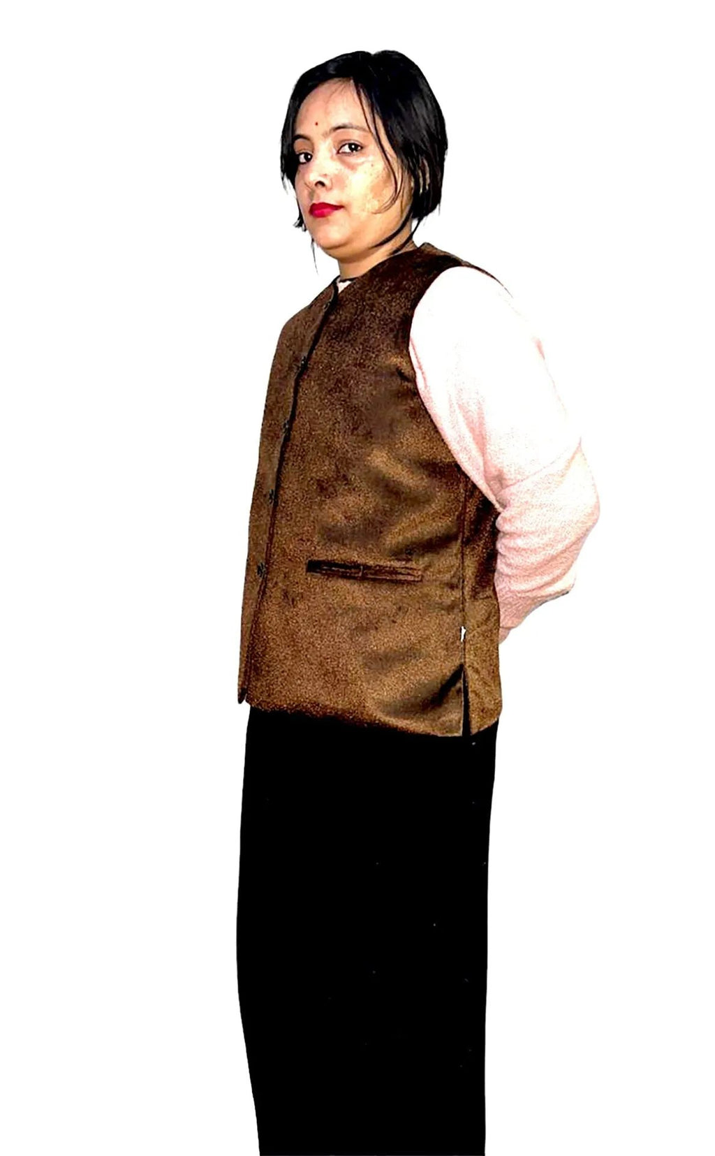 A person with short dark hair wears the aruna kullu handloom Rampuri Nehru jacket FOR LIGHT WINTER AND PARTY WEAR BROWN over a light pink long-sleeve shirt and a long black skirt, standing against a white background with hands behind their back.