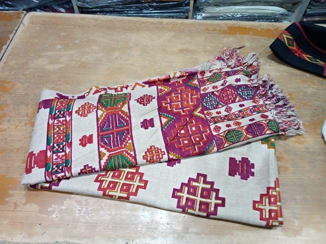 kinnauri shawl kullu and kinnauri shawls kinnauri shawls online kinnauri shawls history  A Pure Yak Wool Pashmina Kinnauri Triple Border printed shawl by aruna kullu handloom, inspired by traditional designs, displayed on a table.