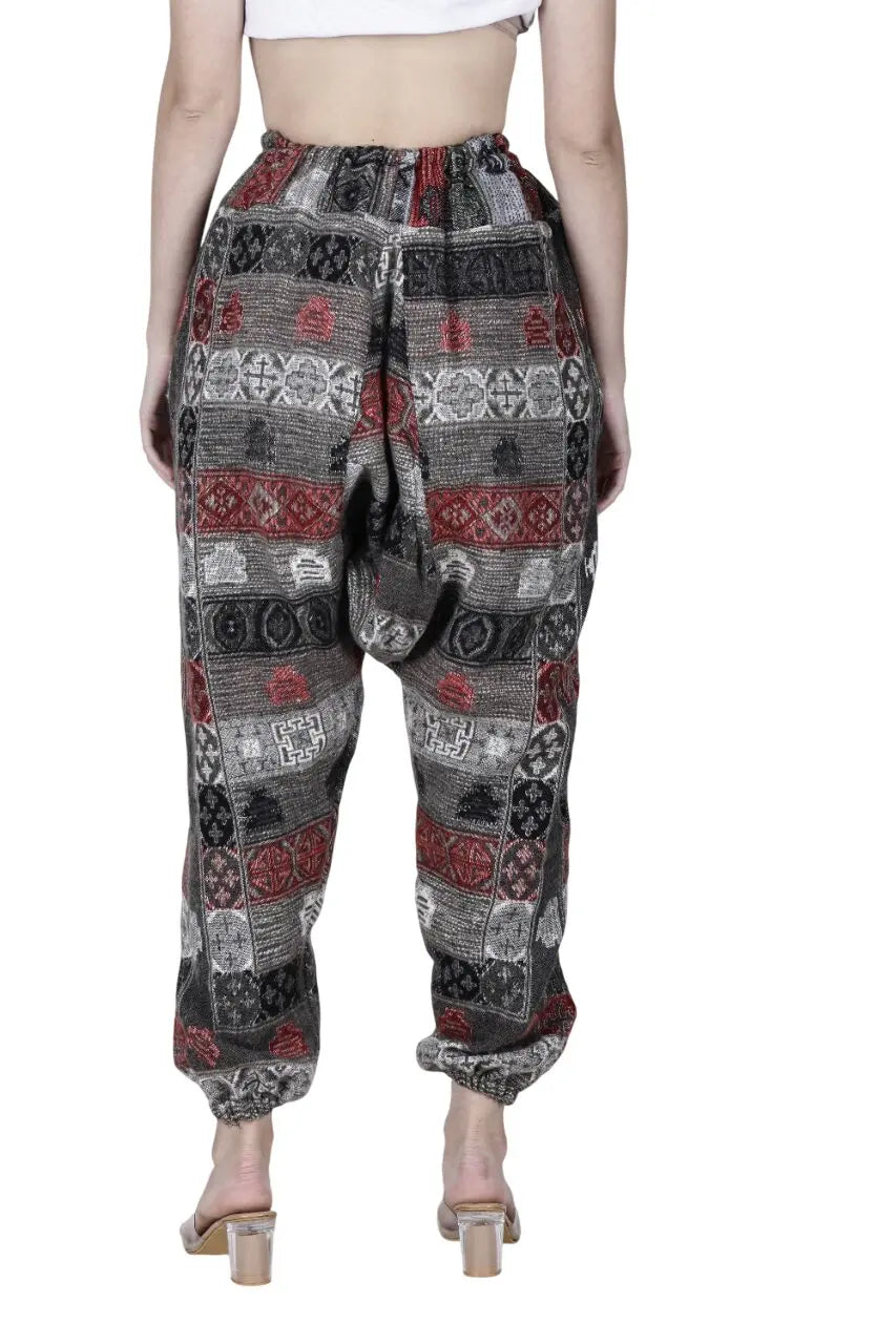 A person is shown from the back wearing Aruna Kullu Handloom's Wool Super Soft Warm Pyjamas with Kullu Patti work, featuring geometric patterns in black, red, and white and styled with clear-heeled sandals. The upper body is partially visible.