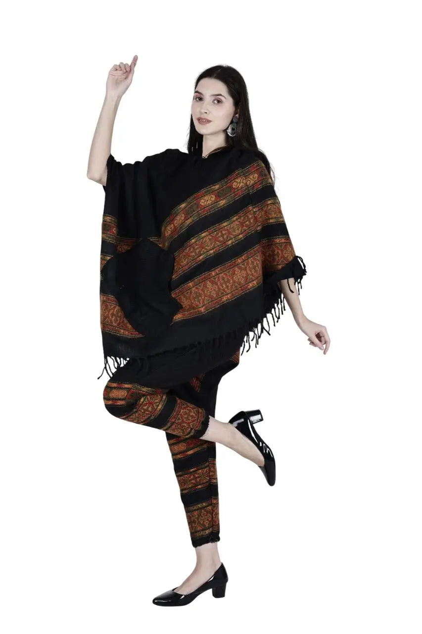 A woman with long dark hair models the aruna kullu handloom kullu shawl combo poncho and pajama black 3 patti, posing on one leg in black shoes against a white background.