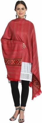 A woman wearing the aruna kullu handloom Kullu Kinnauri Handcrafted Shawl draped over a white kurta and black leggings, paired with sandals and earrings, stands smiling.